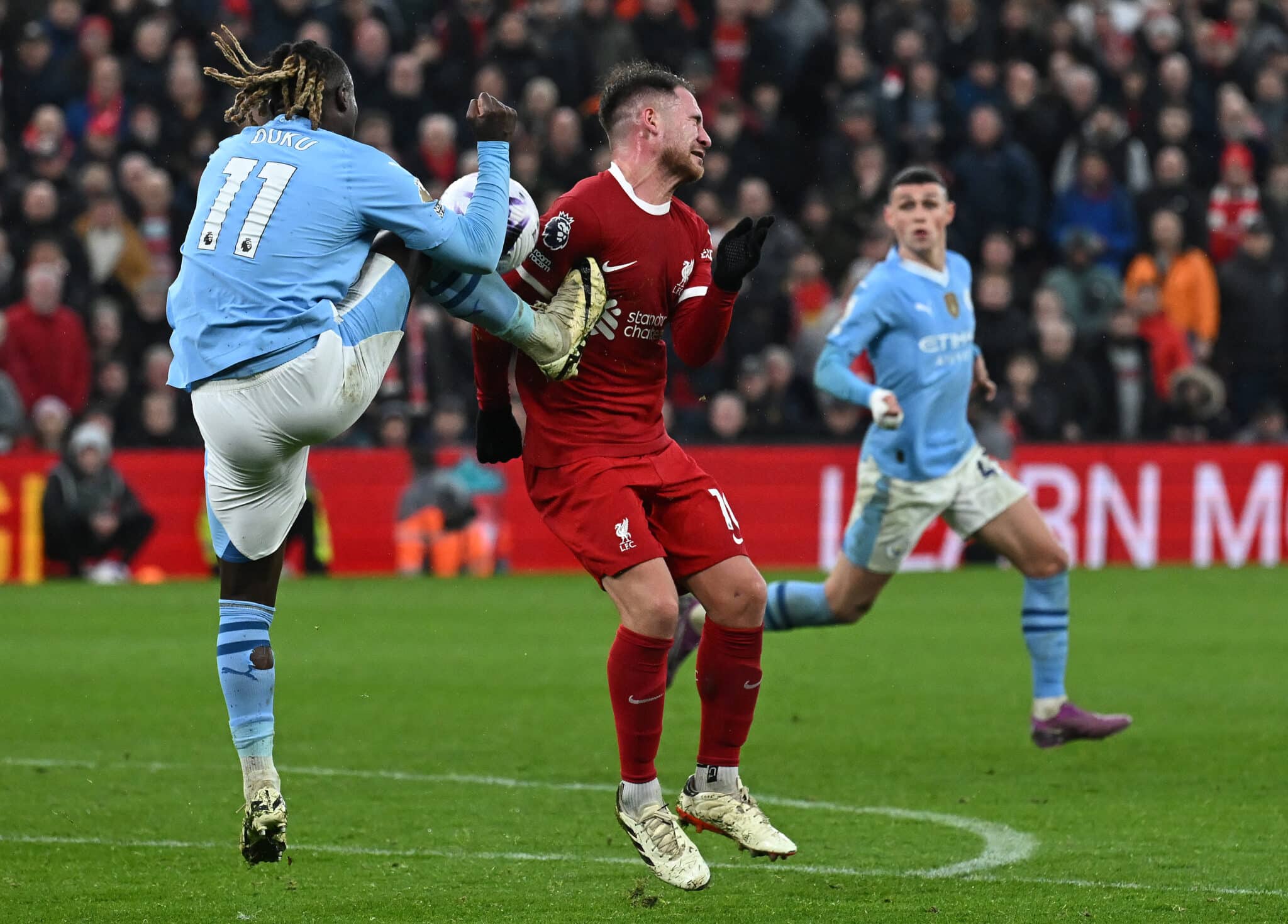 Manchester City's Belgian midfielder #11 Jeremy Doku (L) kicks Liverpool's Argentinian midfielder #10 Alexis Mac Allister during the English Premier League football match between Liverpool and Manchester City at Anfield in Liverpool, north west England on March 10, 2024