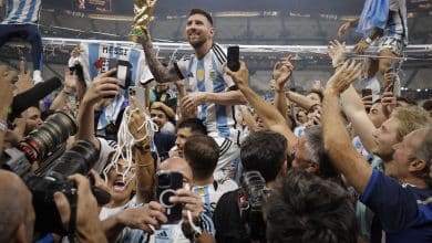 Lionel Messi of Argentina shows off the FIFA World Cup Trophy to fans while he is carried around the pitch on the shoulders of former teammate Sergio Aguero after the team's victory during the FIFA World Cup Qatar 2022 Final match between Argentina and France at Lusail Stadium on December 18, 2022 in Lusail City, Qatar.