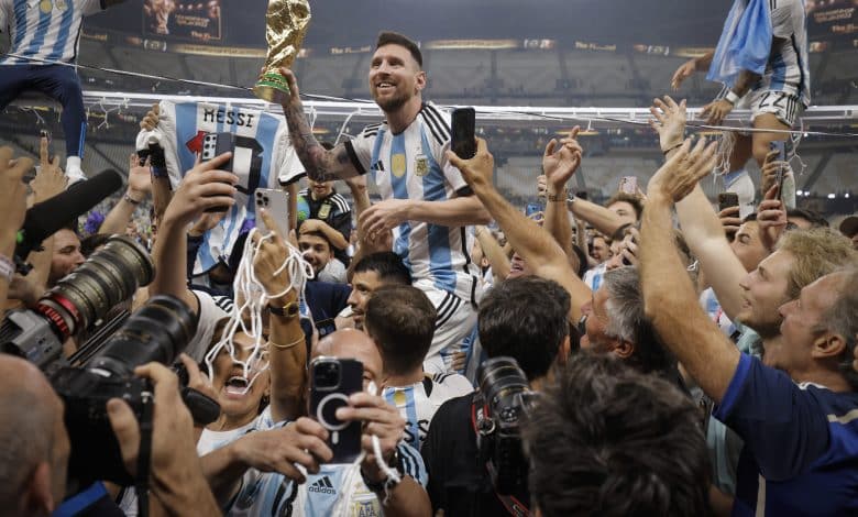 Lionel Messi of Argentina shows off the FIFA World Cup Trophy to fans while he is carried around the pitch on the shoulders of former teammate Sergio Aguero after the team's victory during the FIFA World Cup Qatar 2022 Final match between Argentina and France at Lusail Stadium on December 18, 2022 in Lusail City, Qatar.