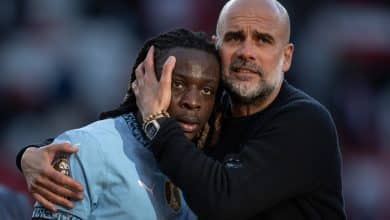 Jeremy Doku of Manchester City interacts with Pep Guardiola, Manager of Manchester City