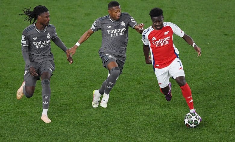 LONDON, ENGLAND - APRIL 08: Bukayo Saka of Arsenal runs with the ball under pressure from Eduardo Camavinga and David Alaba of Real Madrid during the UEFA Champions League 2024/25 Quarter Final First Leg match between Arsenal FC and Real Madrid C.F. at Arsenal Stadium on April 08, 2025 in London, England.
